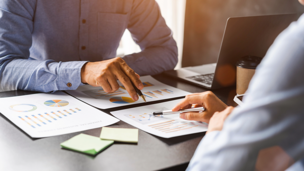 advisor and client reviewing data on papaer charts and a computer