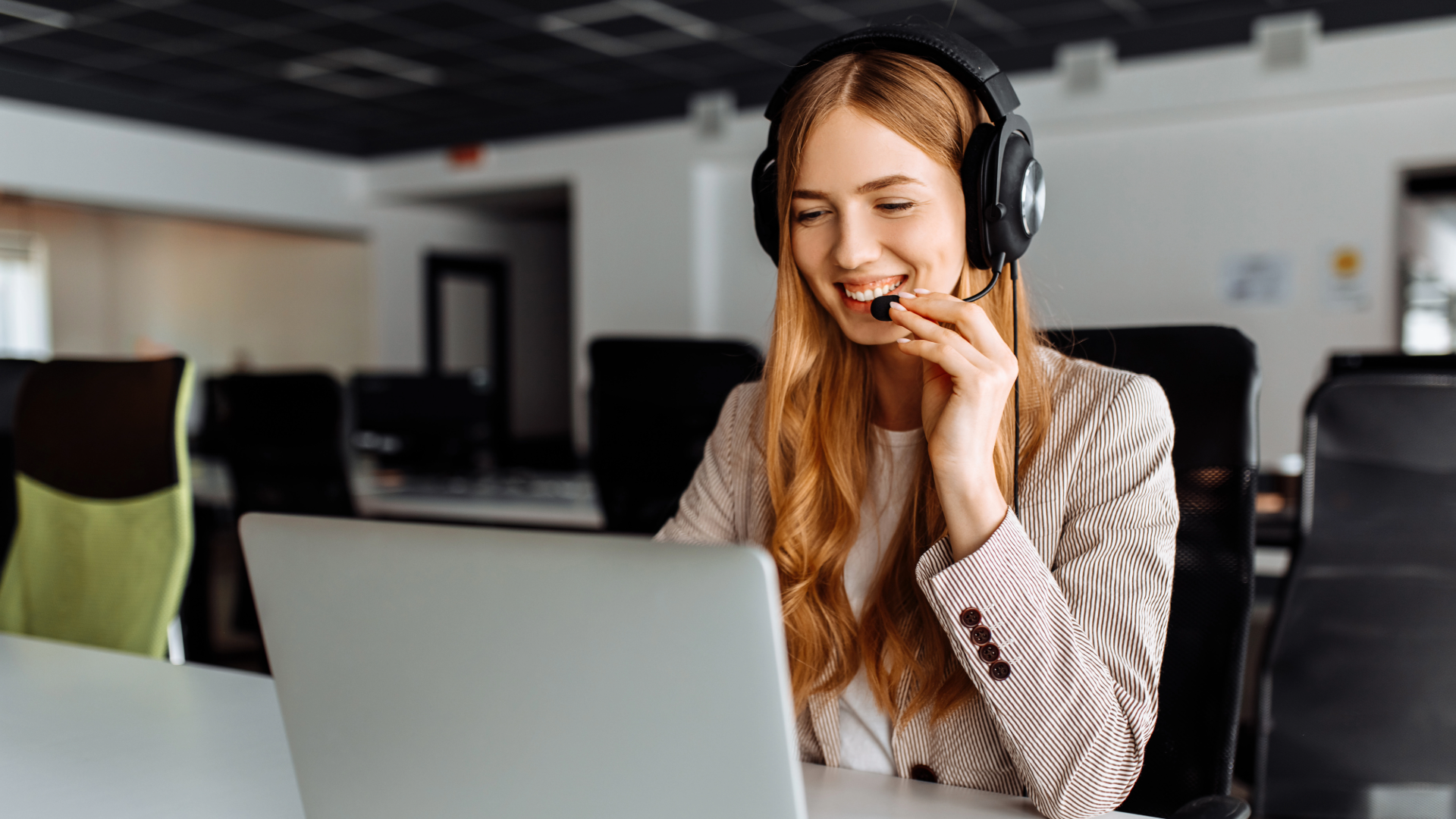 woman withe headset looking at laptop computer