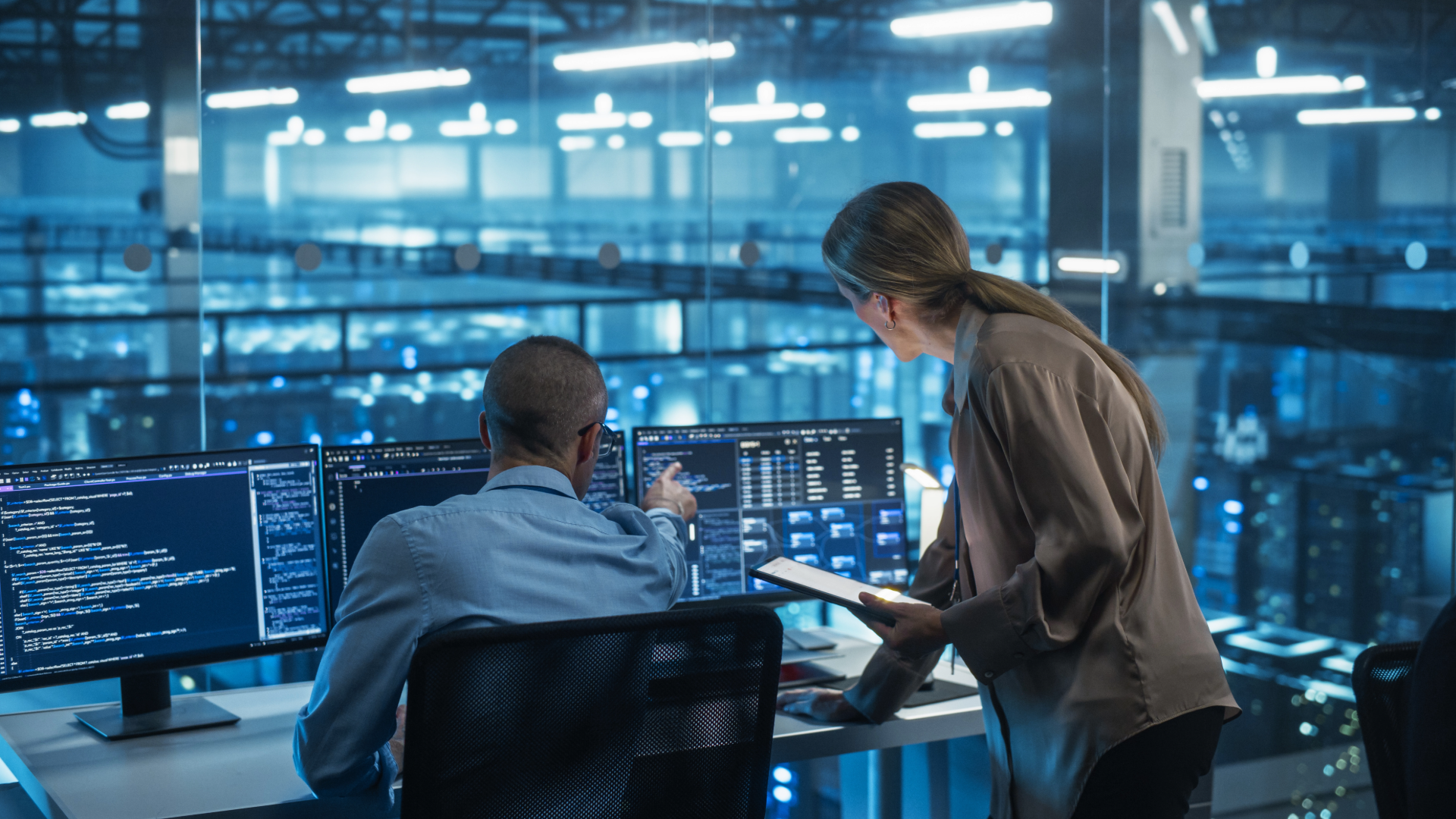 two employees looking at computer monitors in a large office space